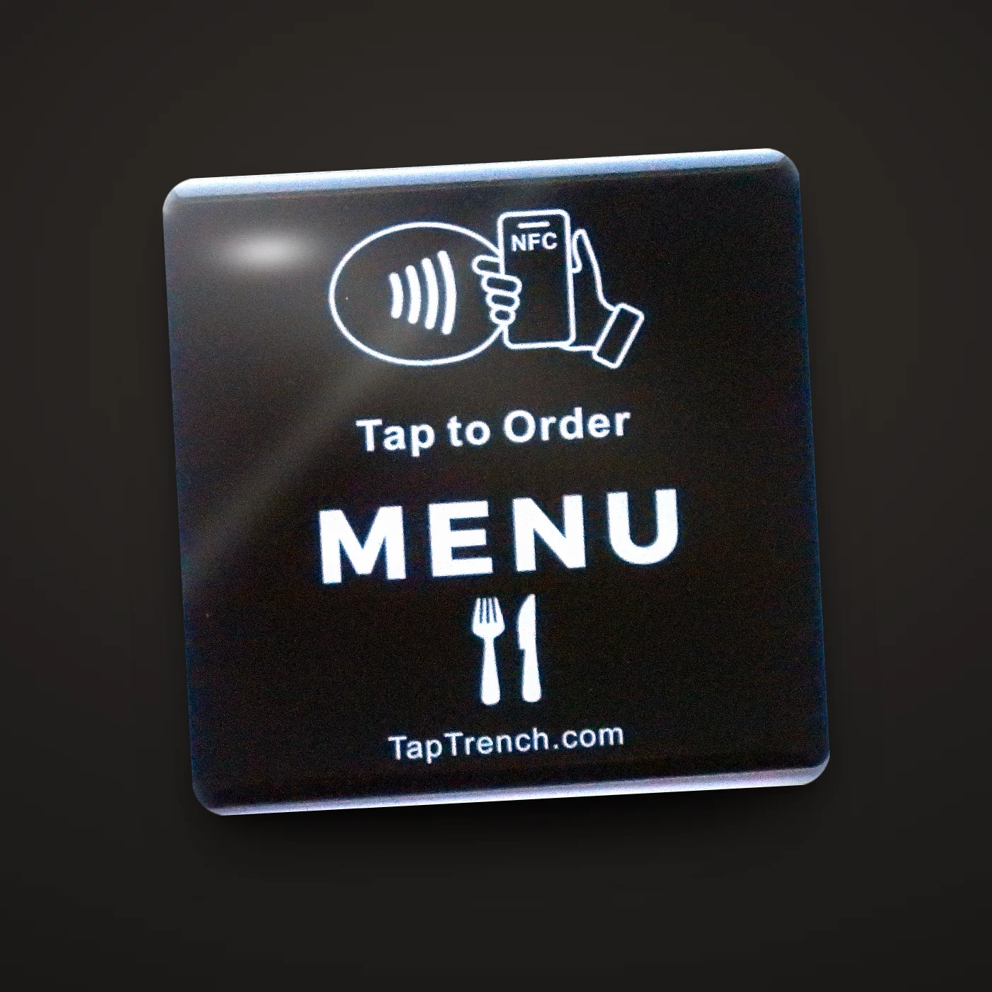 Square menu tap plate close-up on a dark background